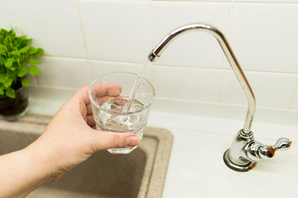 A person filling up a clear glass with filtered water