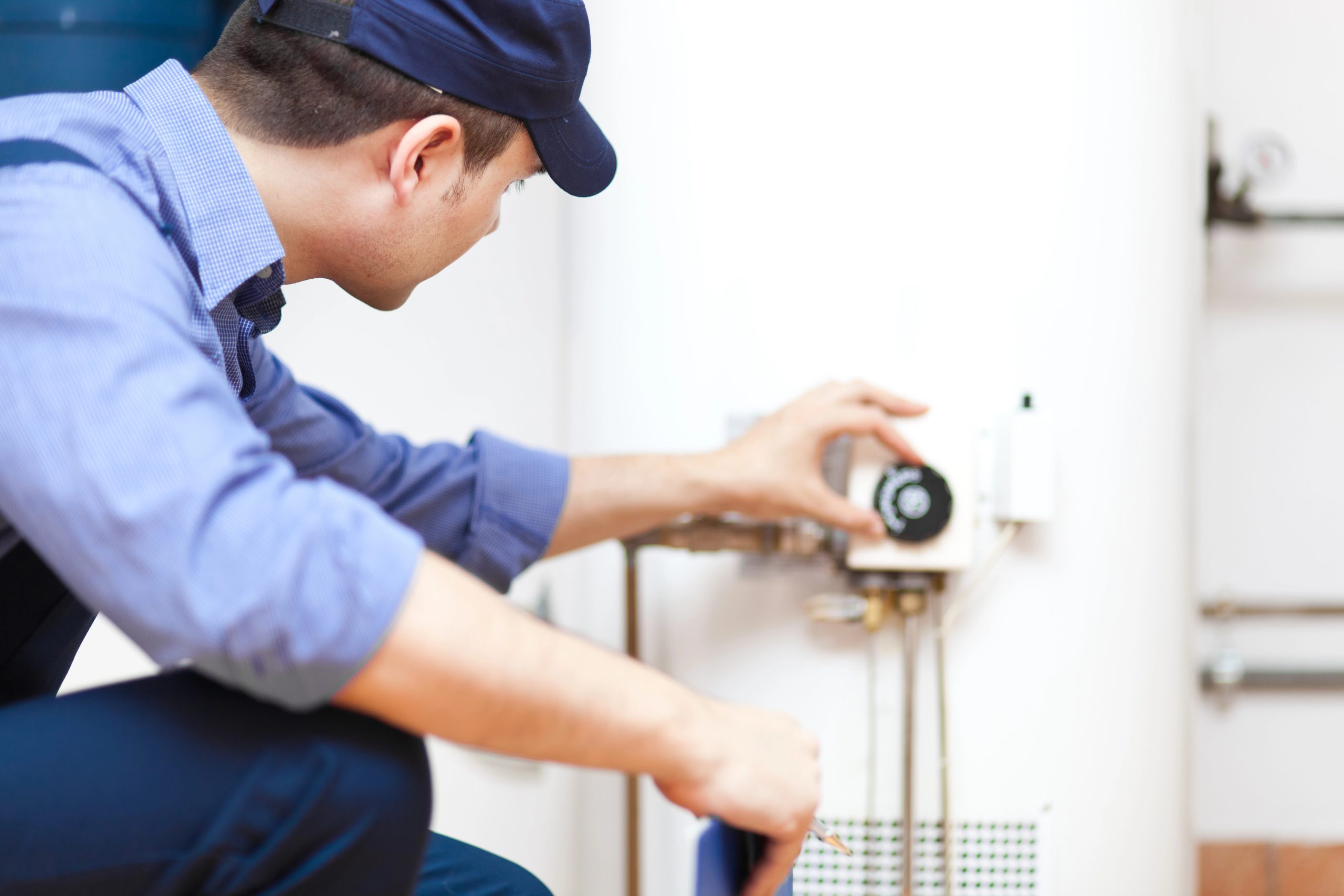 A water heater repairman turning a dial on a home water heater.