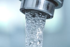A modern running water fixture to a light blue background