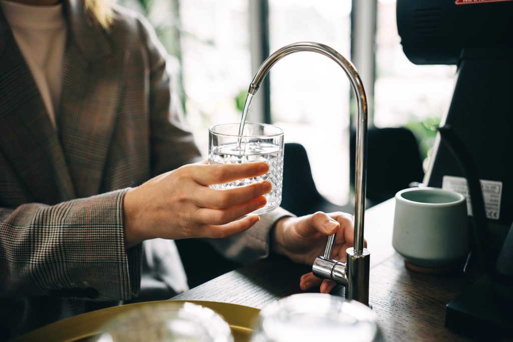 A person filling a glass with RO filtered water