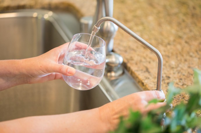 Filling a glass with filtered water from a kitchen drinking water faucet